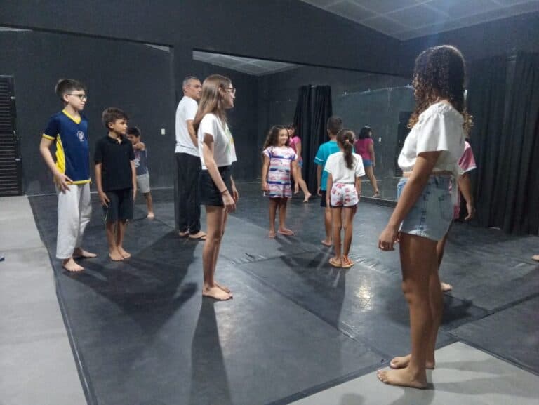 Grupo de crianças realizando atividade corporal em sala.